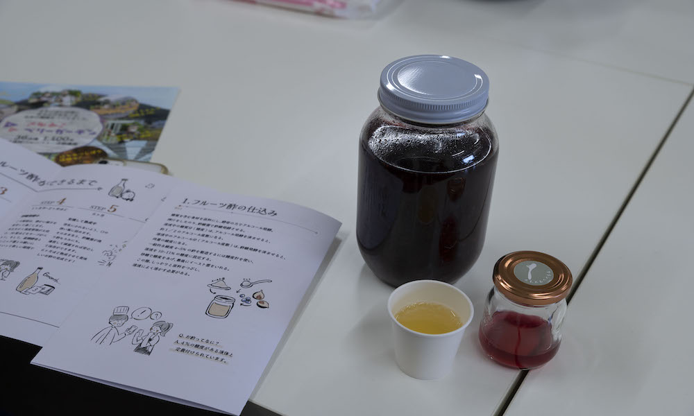 フルーツ発酵酢作りのパンフレットと瓶に入ったブルーベリー酢の様子