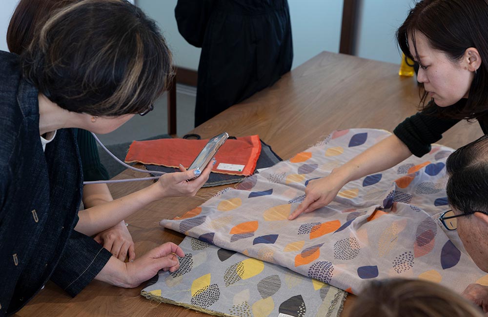 (株)藤高さんのスタッフと新作のパジャマの生地について打ち合わせる様子