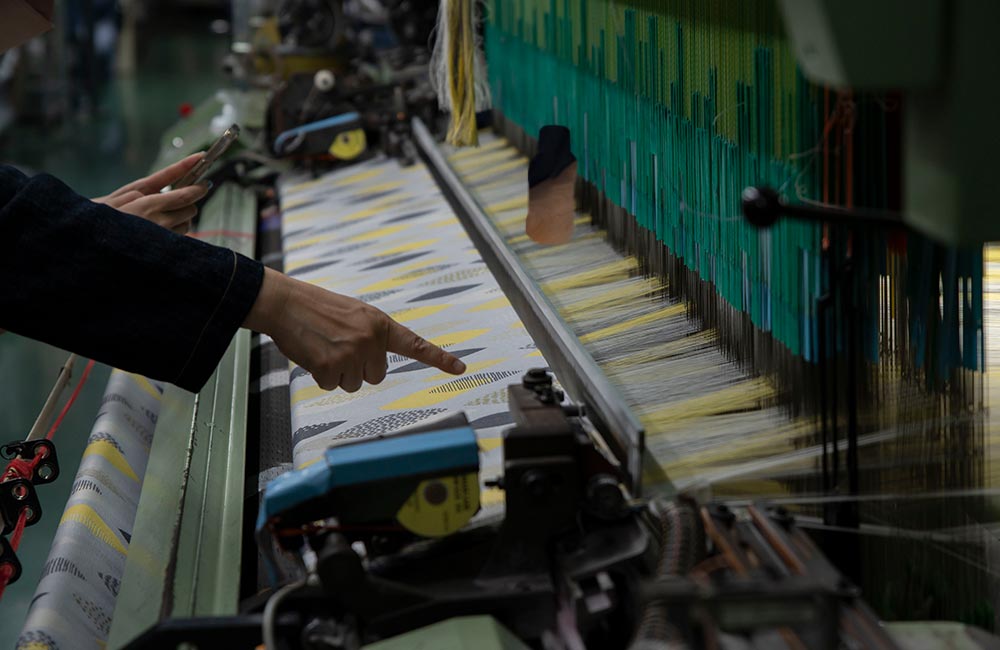 (株)藤高さんのタオル織機でパジャマ屋IZUMMオリジナルのテキスタイルデザインの生地が折られる様子